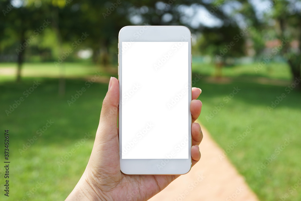 Close up adult hand holding a blank screen smartphone in the park