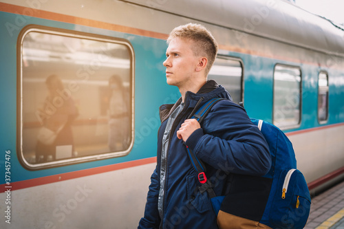 Moscow / Russia - 15 Aug 2020:  A young man with a backpack is standing on the platform at the railway station waiting to Board the train