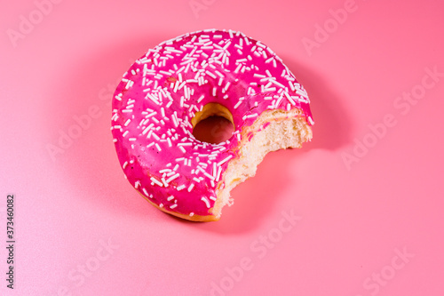Bitten donut with glazed top isolated on a pink background