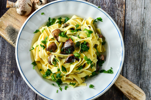 Italian food . Fresh home made tagliatelle vegetarian egg pasta with mushrooms ,parmesan cheese ,fresh parsley and black pepper.