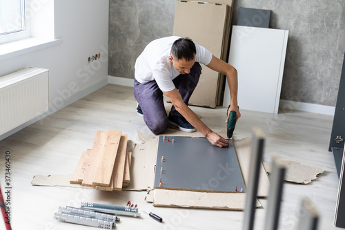 Handsome man assembling furniture at home. photo