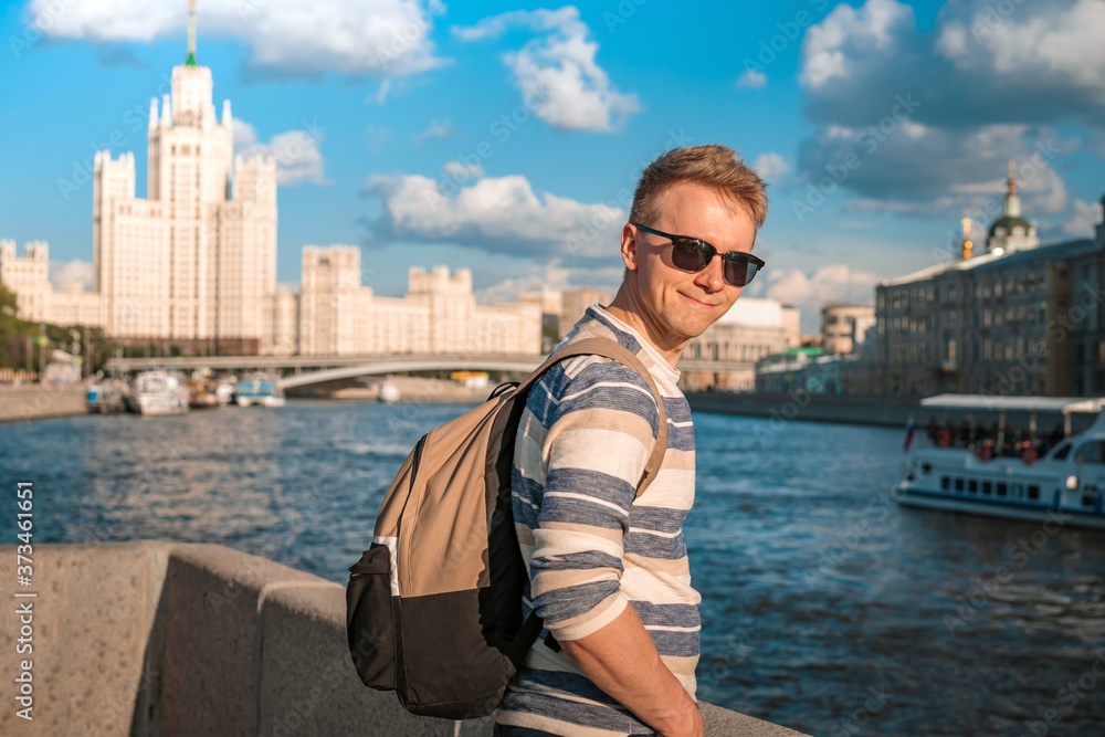 Portrait of a young blond man with the background of the famous high-rise building and the Moscow river on a Sunny summer day