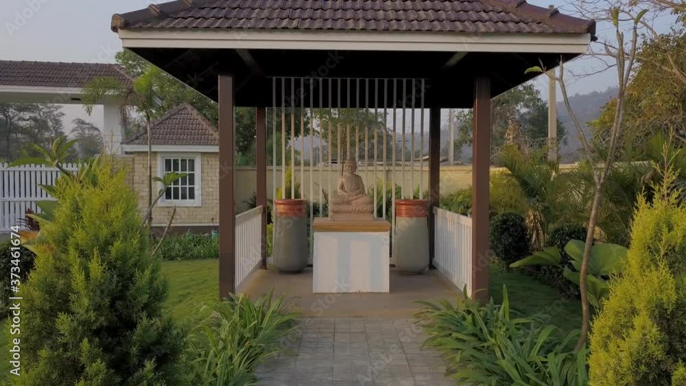 Statue Of Buddha Inside The Gazebo In The Garden Surrounded With Green Plants And Landscape In Mumbai, India. - Pullback Shot