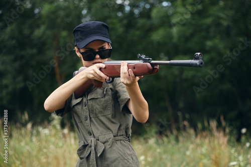 Woman on outdoor Fresh air is aimed with weapons in nature green leaves