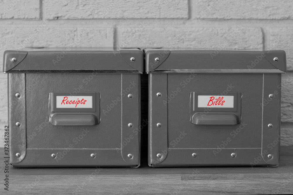 Storage boxes with receipts and bills written on labels in red. With a grey brick background Storage boxes with receipts and bills written on labels in red. With a grey brick background
