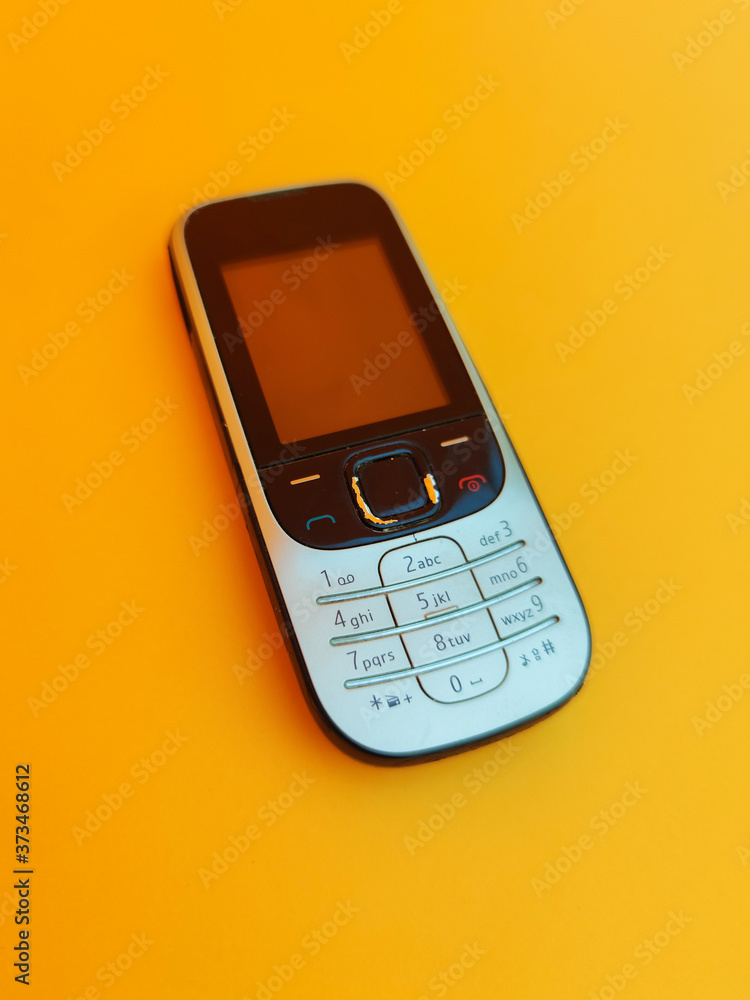 Old mobile phone. Cell phone isolated on orange background, vintage mobile phone, vintage style Old mobile phone. Cell phone isolated on orange background, vintage mobile phone, vintage style