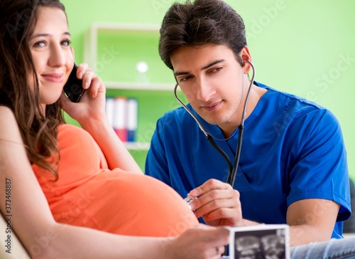 Pregnant woman visiting male gynecologyst at the clinic photo