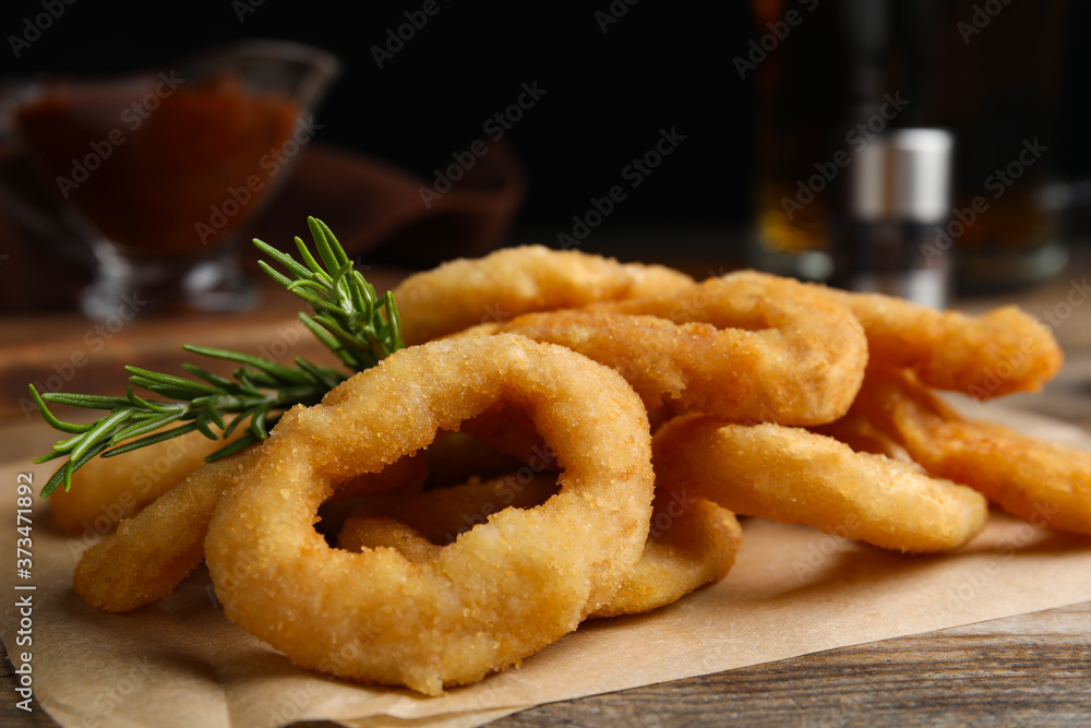Pile of delicious crunchy fried onion rings with rosemary on wooden table, closeup Pile of delicious crunchy fried onion rings with rosemary on wooden table, closeup