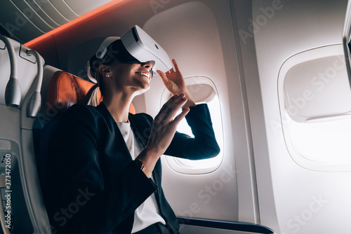 Smiling woman in airplane experiencing virtual reality in modern headset