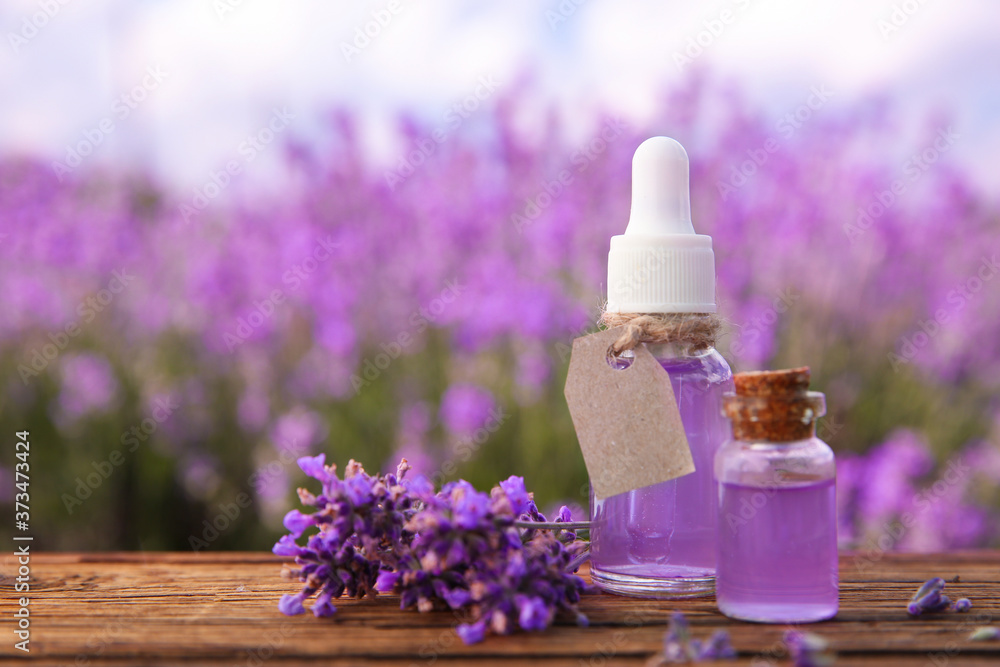 Bottles of natural essential oil and lavender flowers on wooden table. Space for text Bottles of natural essential oil and lavender flowers on wooden table. Space for text