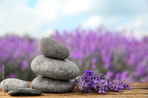 Spa stones and fresh lavender flowers on wooden table outdoors  closeup. Space for text