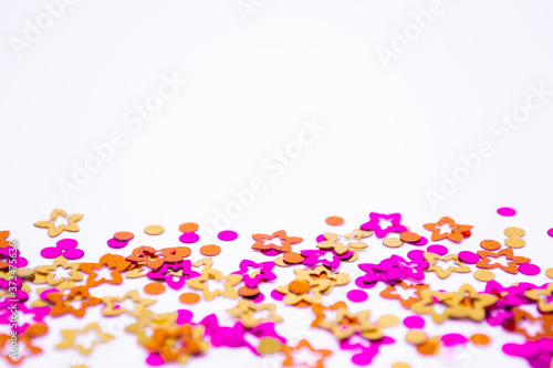 Scattered round confetti and in the form of flowers pink, gold and orange color on a white background. Copy space. Spring and summertime, birthday and wedding concept
