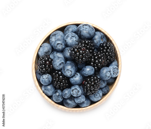 Blueberries and blackberries in bowl on white background, top view
