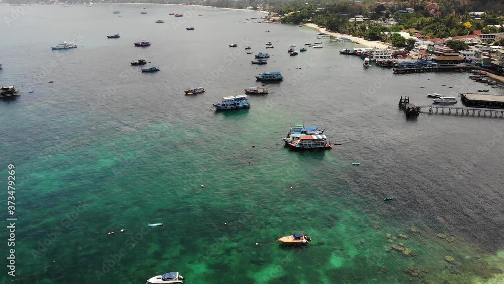 Obraz premium Boats in calm sea in port. Drone view of fishing and dive boats floating on tranquil surface of blue sea in harbor of tropical exotic paradise Koh Tao Island on sunny day in Thailand