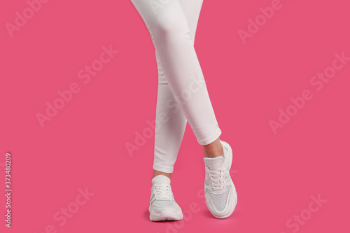 Woman wearing sneakers on pink background, closeup