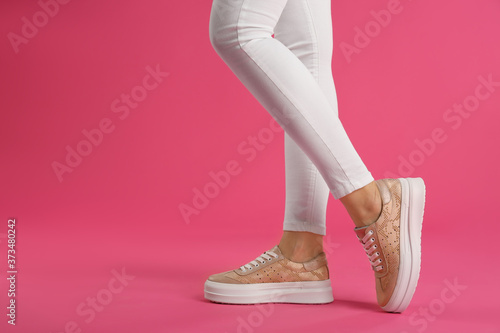 Woman wearing shoes on pink background, closeup. Space for text