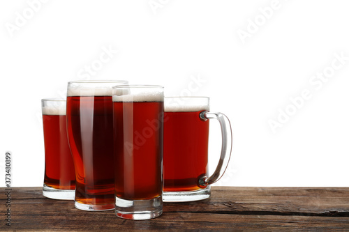 Glasses of delicious kvass on wooden table, white background
