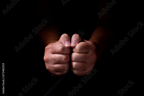 Male hands emerging from the darkness. Hands on a black background.
