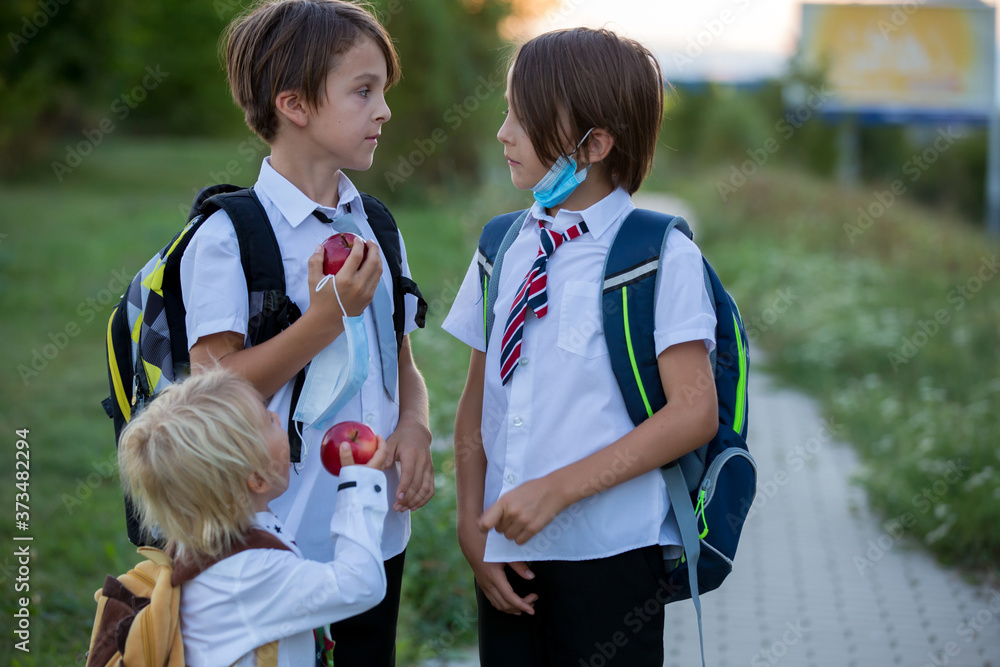 Obraz premium School children, boys wearing medical masks, going back to school after the summer vacation