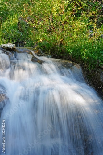 View of a running waterfall over boulders in the Laurance S. Rockefeller Preserve, a nature refuge on Phelps Lake in Grand Teton National Park in Jackson, Wyoming, United States