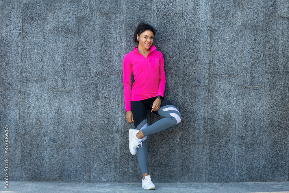 Black girl in sportswear posing over grey stone wall Black girl in sportswear posing over grey stone wall