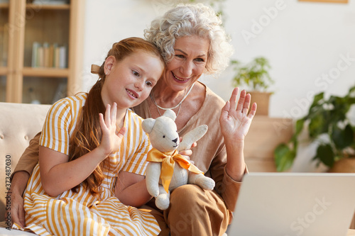 Bilde på lerret Warm toned portrait of smiling senior woman waving at camera during video call w