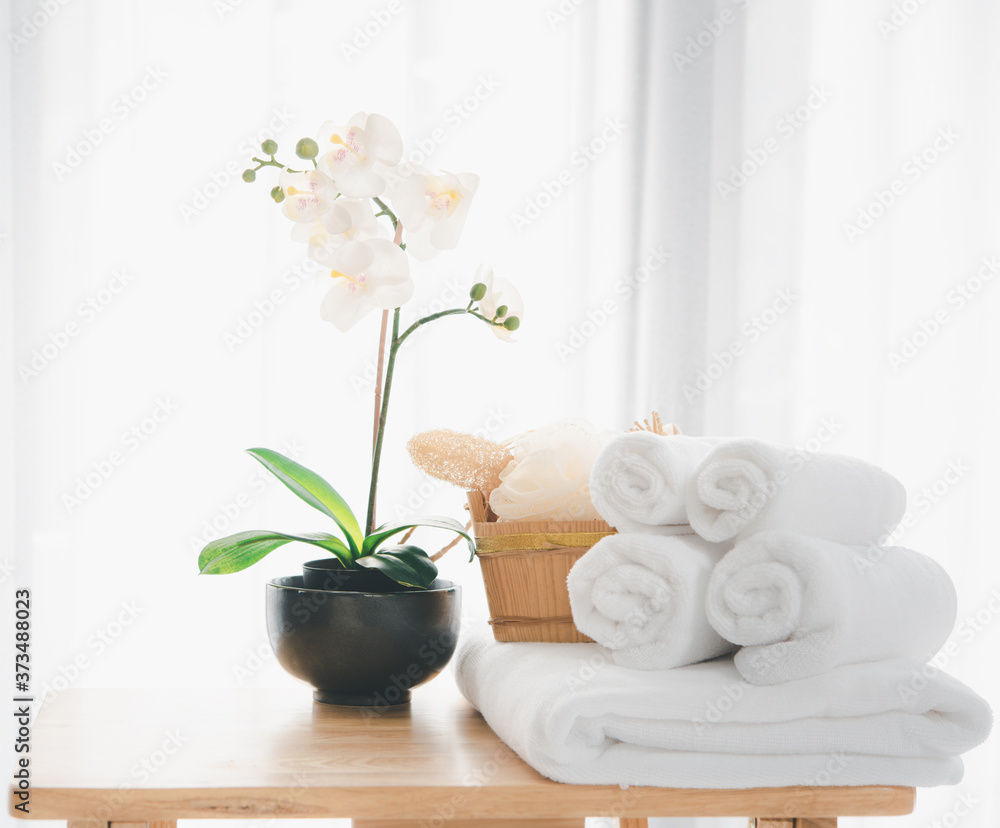 Spa products with white towels,soap,luffa scrub,comb and beautiful orchid flower in clean white room