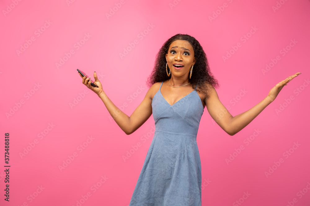 pretty black lady looking surprised and holding a phone with arms stretched out pretty black lady looking surprised and holding a phone with arms stretched out