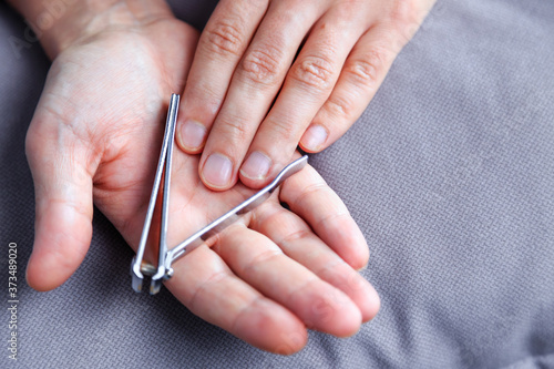 Man cutting nails using nail clipper. Nail clipper in the hands of a man