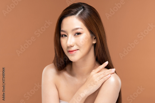 Beautiful Young Asian Woman Looking While Touching Shoulder feeling so happy and cheerful with healthy Clean and Fresh skin,isolated on Beige background,Beauty Cosmetic Concept