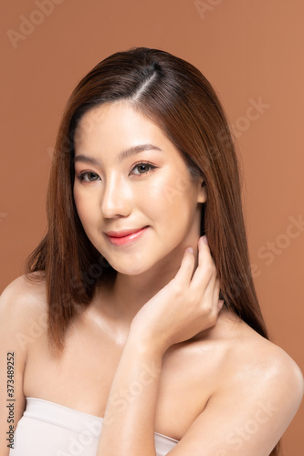 Beautiful Asian young woman touching neck smile with clean and fresh skin Happiness and cheerful with positive emotional,isolated on Beige background,Beauty and Cosmetics Concept