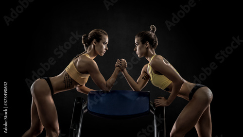 Fotografía two young fitness woman, arm wrestling in gym