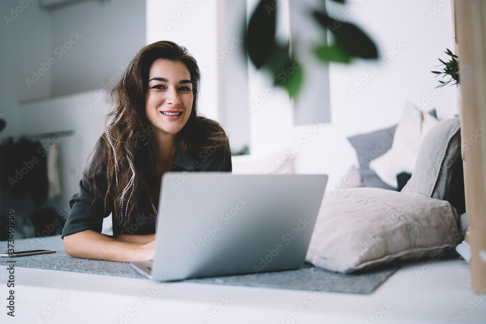 Positive caucasian hipster girl 20s looking at camera making booking online using technology at home, portrait of happy prosperous female blogger using laptop computer for remote job at home Positive caucasian hipster girl 20s looking at camera making booking online using technology at home, portrait of happy prosperous female blogger using laptop computer for remote job at home