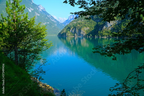 Fototapeta Naklejka Na Ścianę i Meble -  The Lago del Mis is lake in Belluno, Veneto, Italy,  looks very beautiful with its green colors. It's morning and sunrise. Beautiful italian nature. The Dolomites are a mountain range located in Italy
