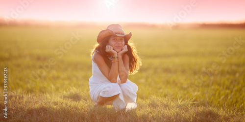 Obraz na płótnie Niña con sombrero tejano en el campo al atardecer w salonie
