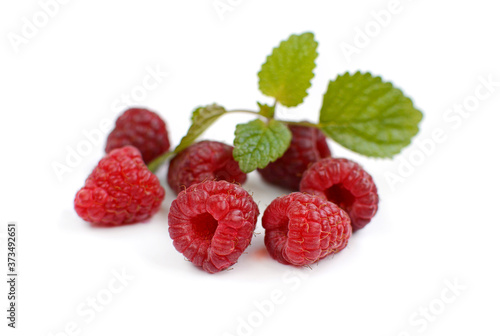 Several ripe juicy raspberries and mint leaf on a white background.