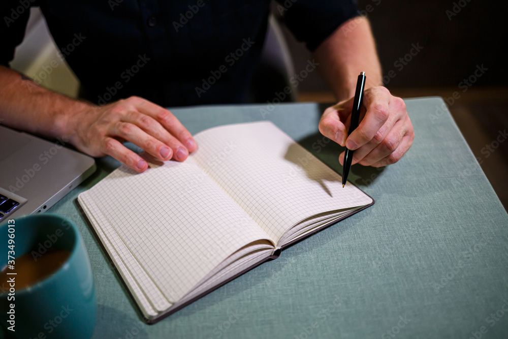 A man makes a record with a pen in a notebook. A book for recording important matters. Diary of a businessman A man makes a record with a pen in a notebook. A book for recording important matters. Diary of a businessman