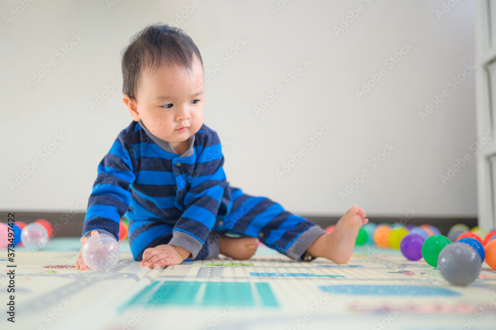 Kid playing with ball on soft carpet in children room