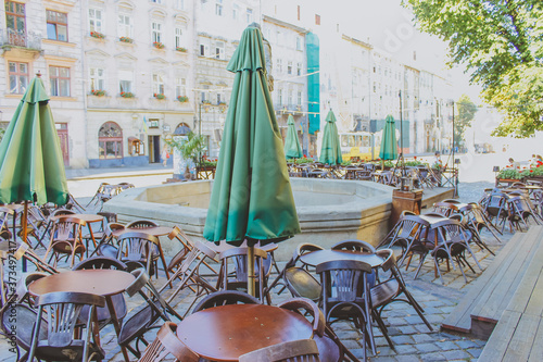 Tables and chairs in empty  restaurant.
Open outdoors cafe with chairs and tables.