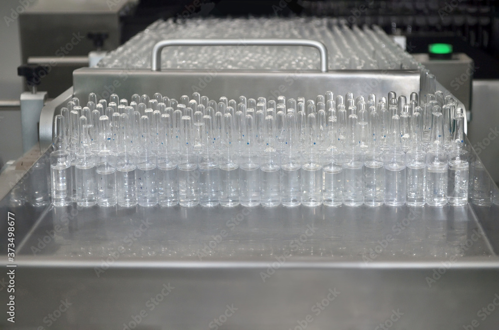 Glass ampoules with medicine are on the table of an automated production line Glass ampoules with medicine are on the table of an automated production line