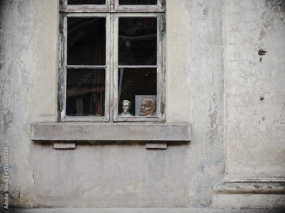 A portrait of Lenin and a bust of Dzerzhinsky outside the window of the apartment.