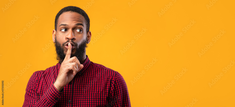 Obraz premium Funny black man making silence gesture with hand