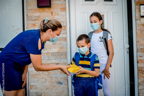 Boy and girl going back to school. They are wearing a protective face masks.