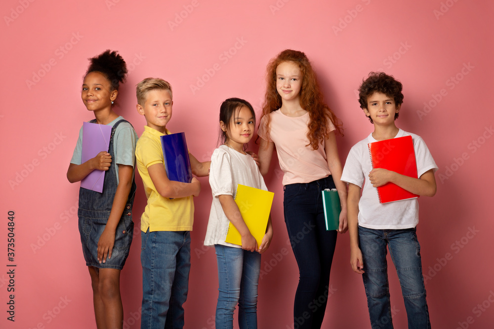 Ready for school. Multinational classmates holding notebooks over pink background Ready for school. Multinational classmates holding notebooks over pink background
