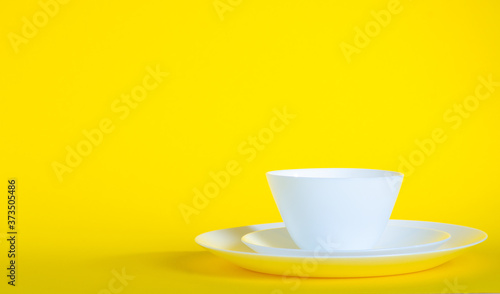 Empty white dishes plates on yellow background