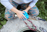 Young women installing or repairing system of water filtration near opened hatch on the street in the home yard