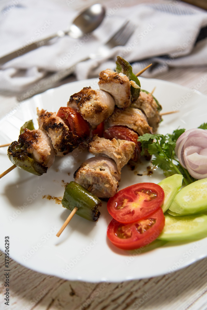 Heap of chicken kebab meat on a plate with salad condiments