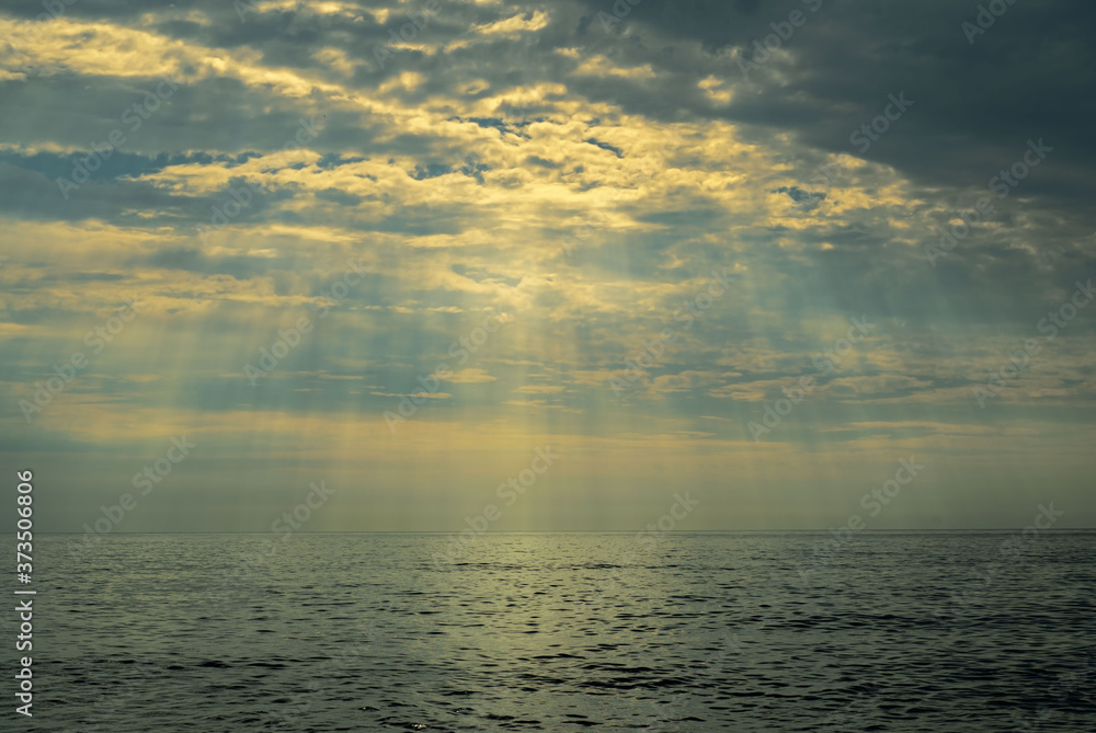 Sun rays shining through the clouds over the sea Sun rays shining through the clouds over the sea