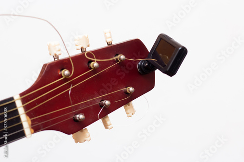 Guitar tuner. Wooden guitar on a white background. Guitar tuning.