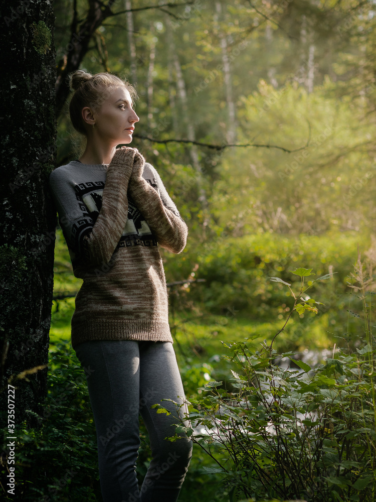 A young woman walks in the morning forest, enjoys the scent of flowers and rests in silence. Summer, spring, travel, vacation or relaxation concept. A young woman walks in the morning forest, enjoys the scent of flowers and rests in silence. Summer, spring, travel, vacation or relaxation concept.